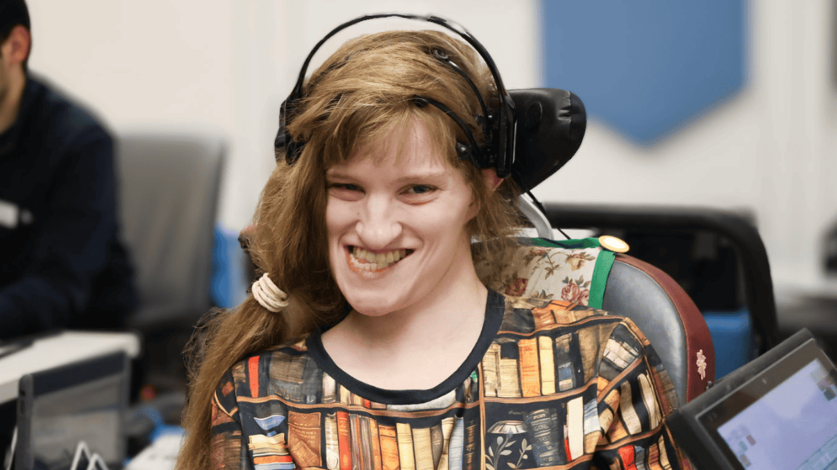 Young woman with headphones and assistive device smiling during therapy session.