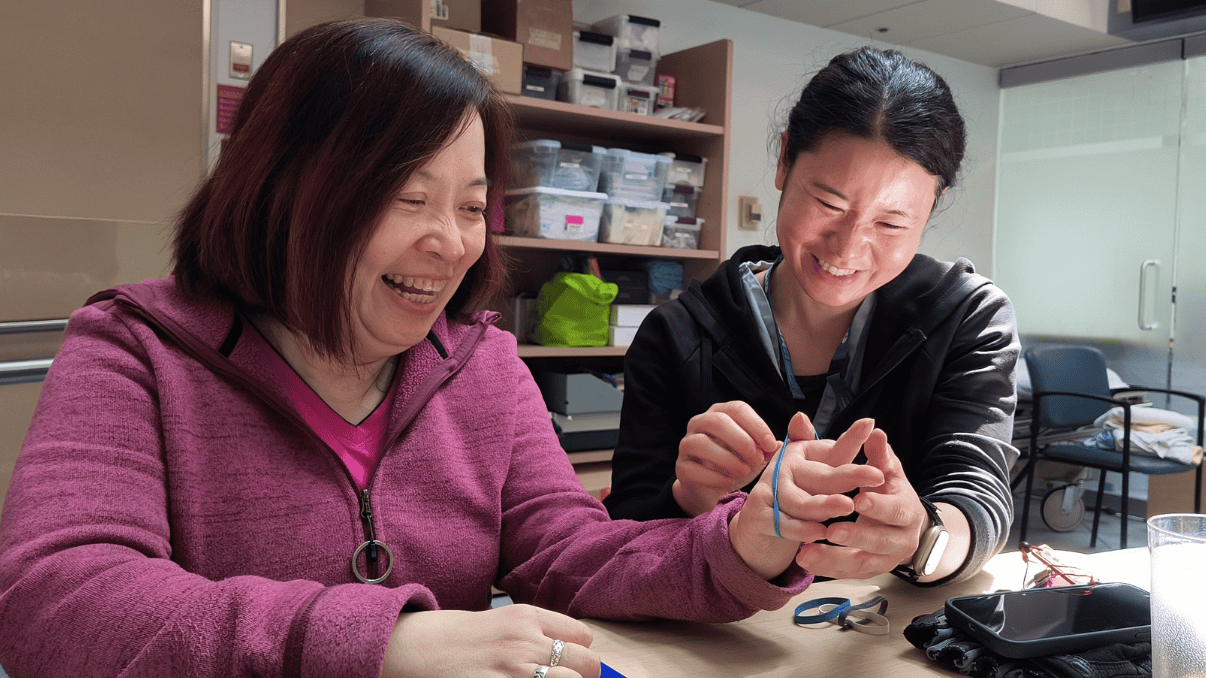 Two women smiling and engaging with a smartphone in a medical setting.