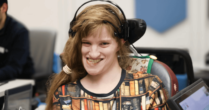 Young woman with headphones and assistive device smiling during therapy session.