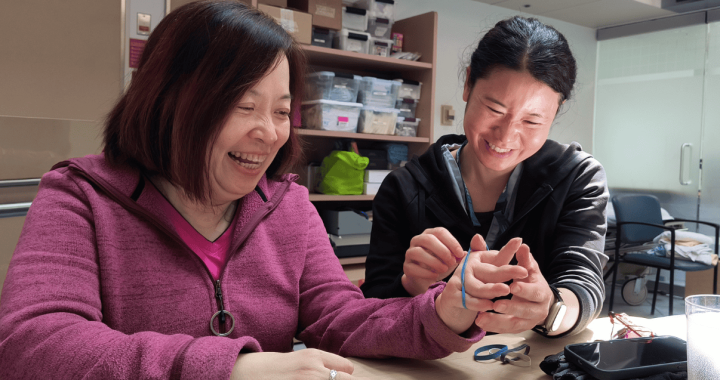 Two women smiling and engaging with a smartphone in a medical setting.