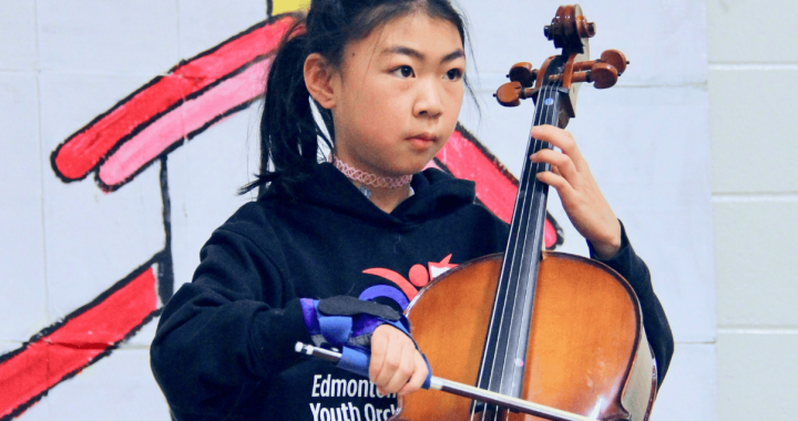 Young girl playing cello during a music therapy session at Glenrose Hospital.